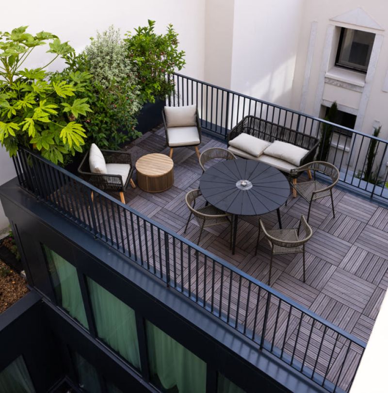 Terrasse sur toit avec plantes, fauteuils et table ronde